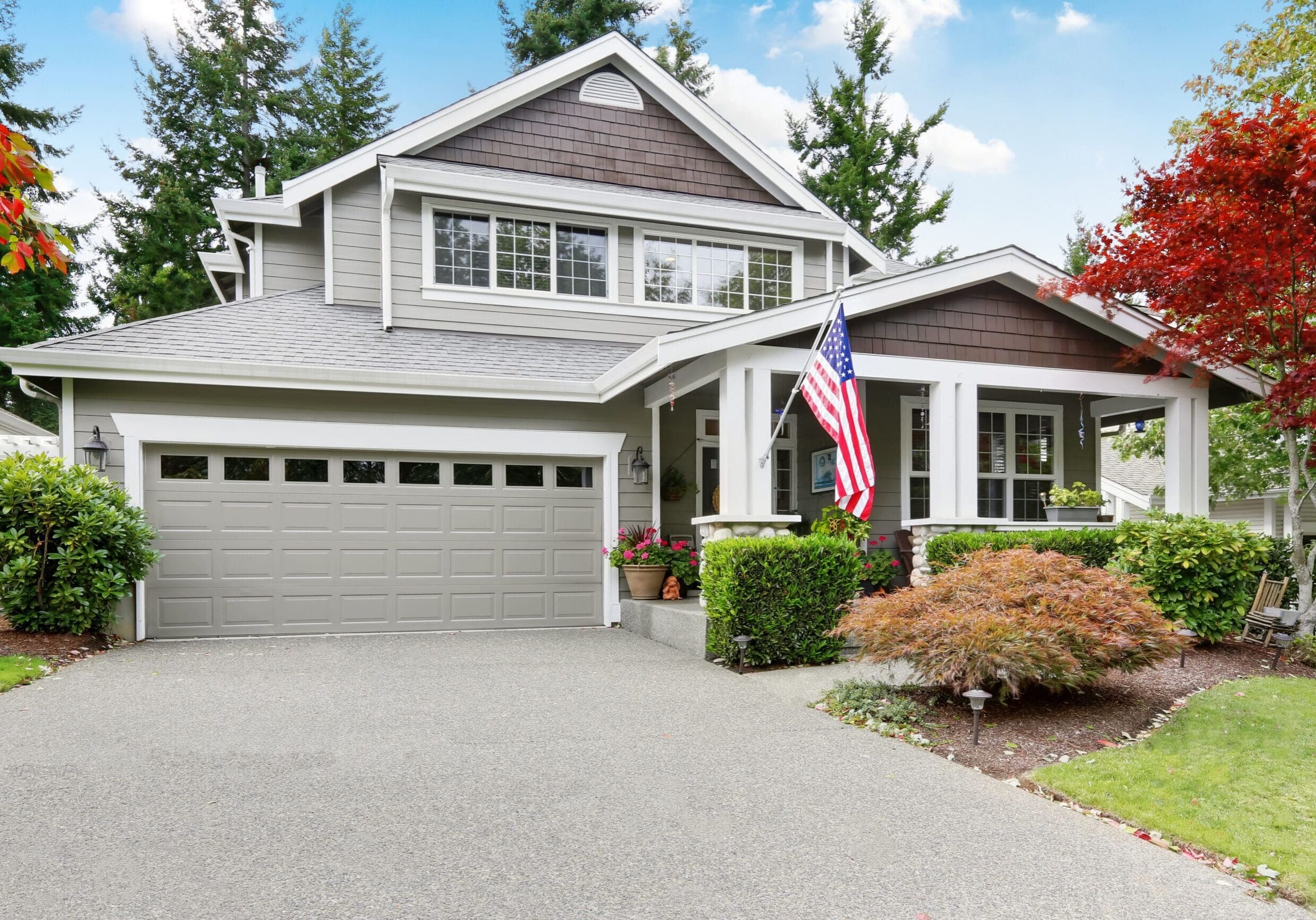 Modern craftsman home with large windows, front porch, and American flag in Duluth, Georgia, surrounded by landscaped yard.