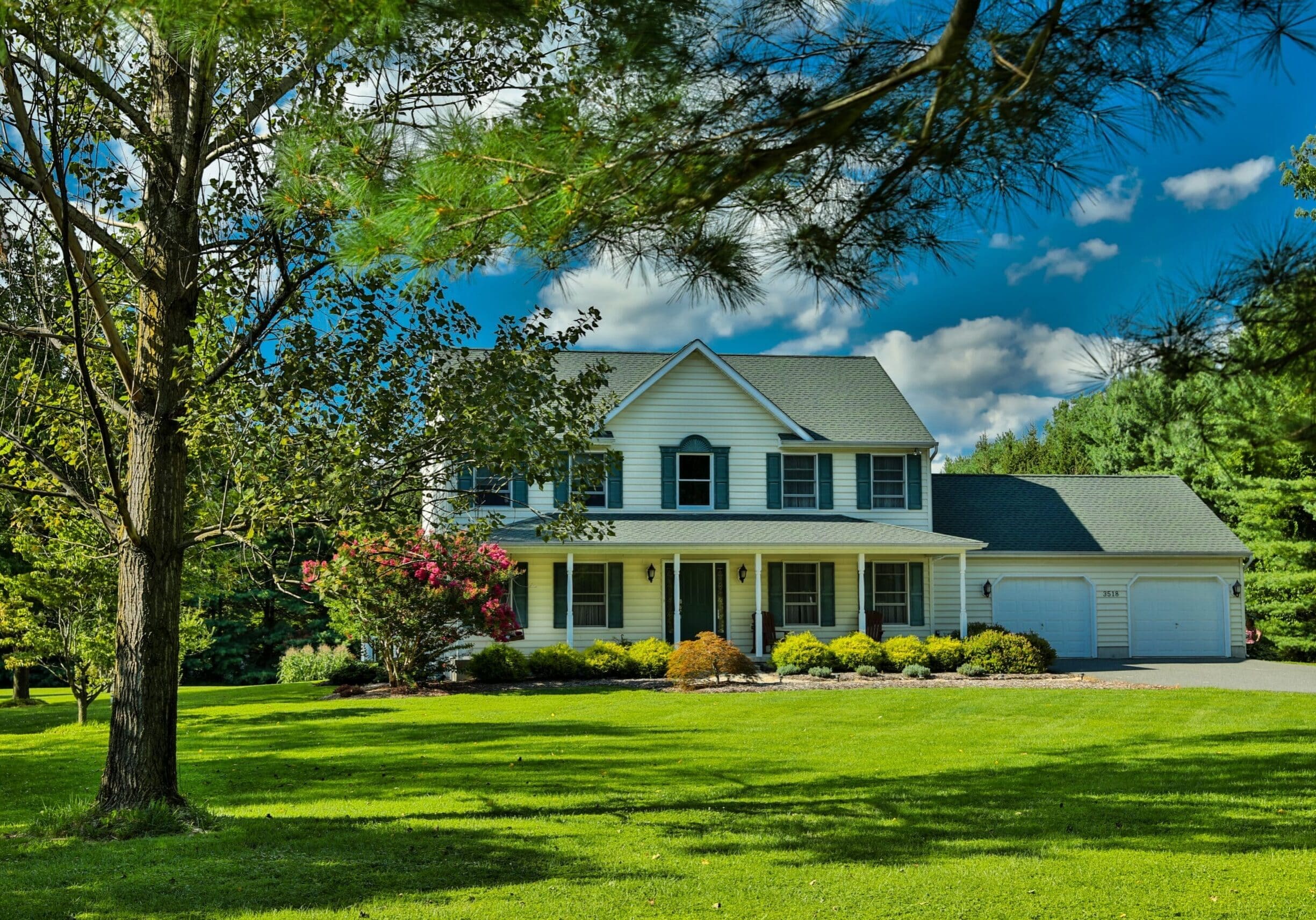 Traditional two-story home with white siding, black shutters, and double-hung windows in John’s Creek, Georgia, on a sunny day.
