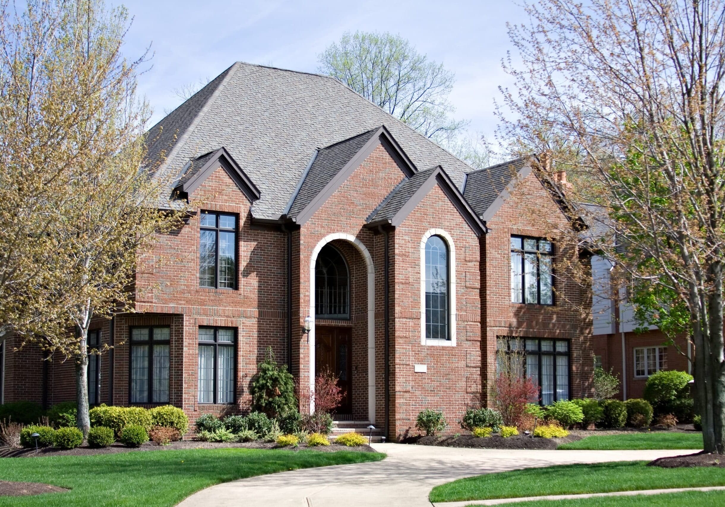 Elegant brick home with arched and rectangular windows, steep gabled roof, and manicured landscaping in Grayson, Georgia.
