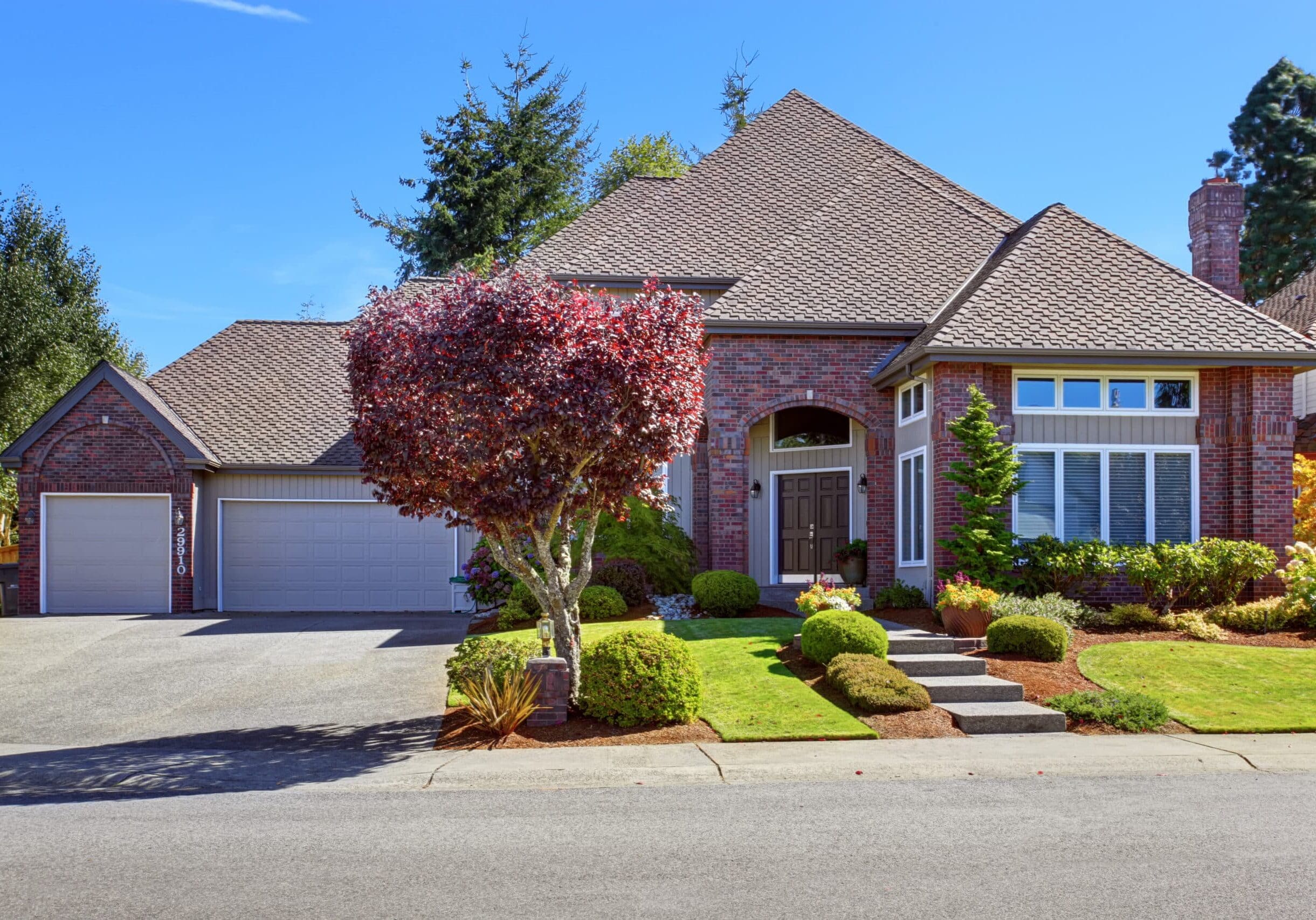 Brick home in Milton, Georgia, with large grid windows, double front door under arched entry, and manicured landscaping.