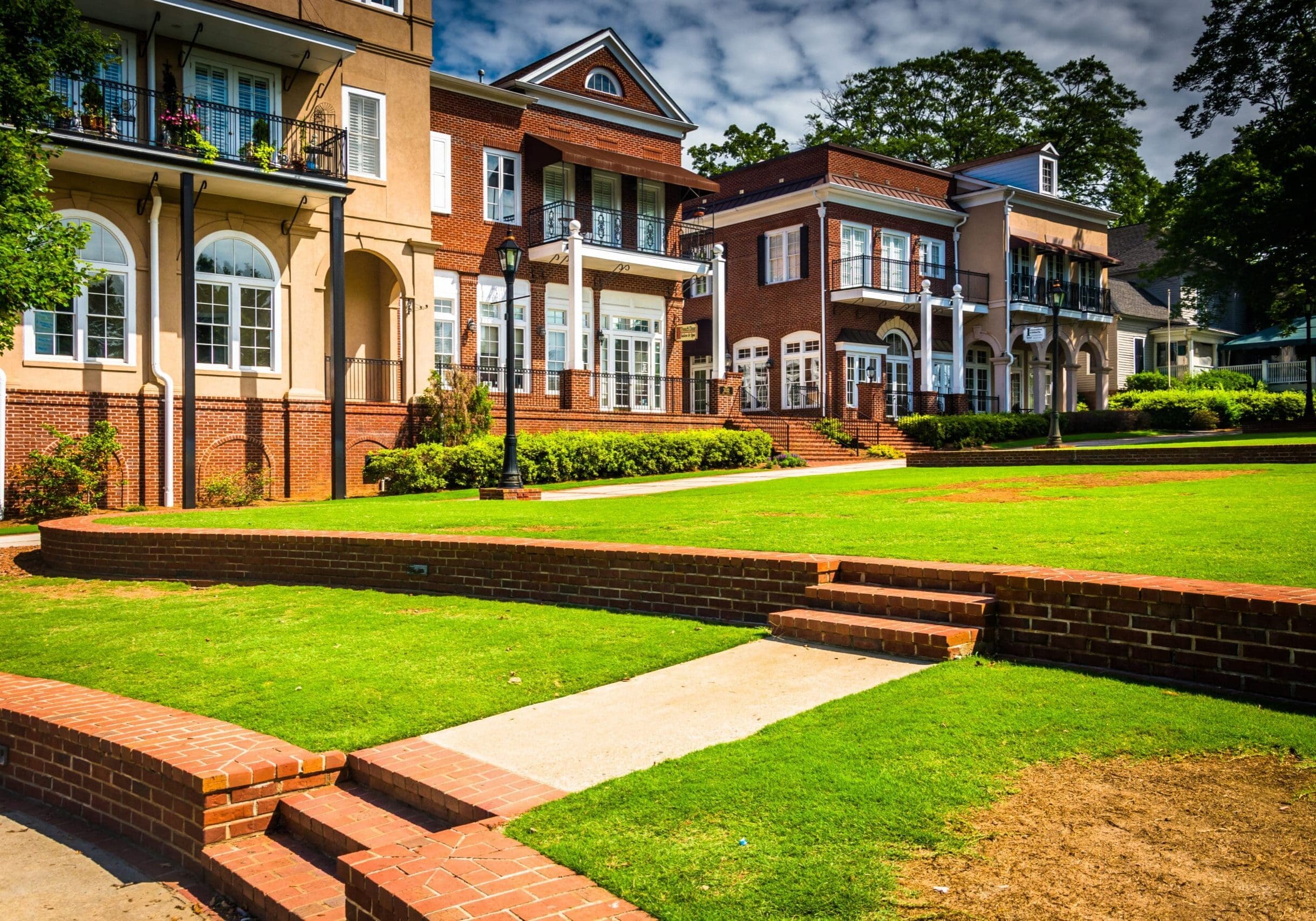 Row of brick and stucco buildings with large windows and balconies overlooking a green lawn in downtown Duluth, Georgia.